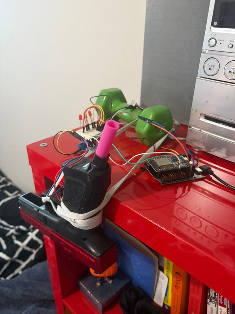 The ESP32 alarm prototype and gel blaster mounted to a red shelf.