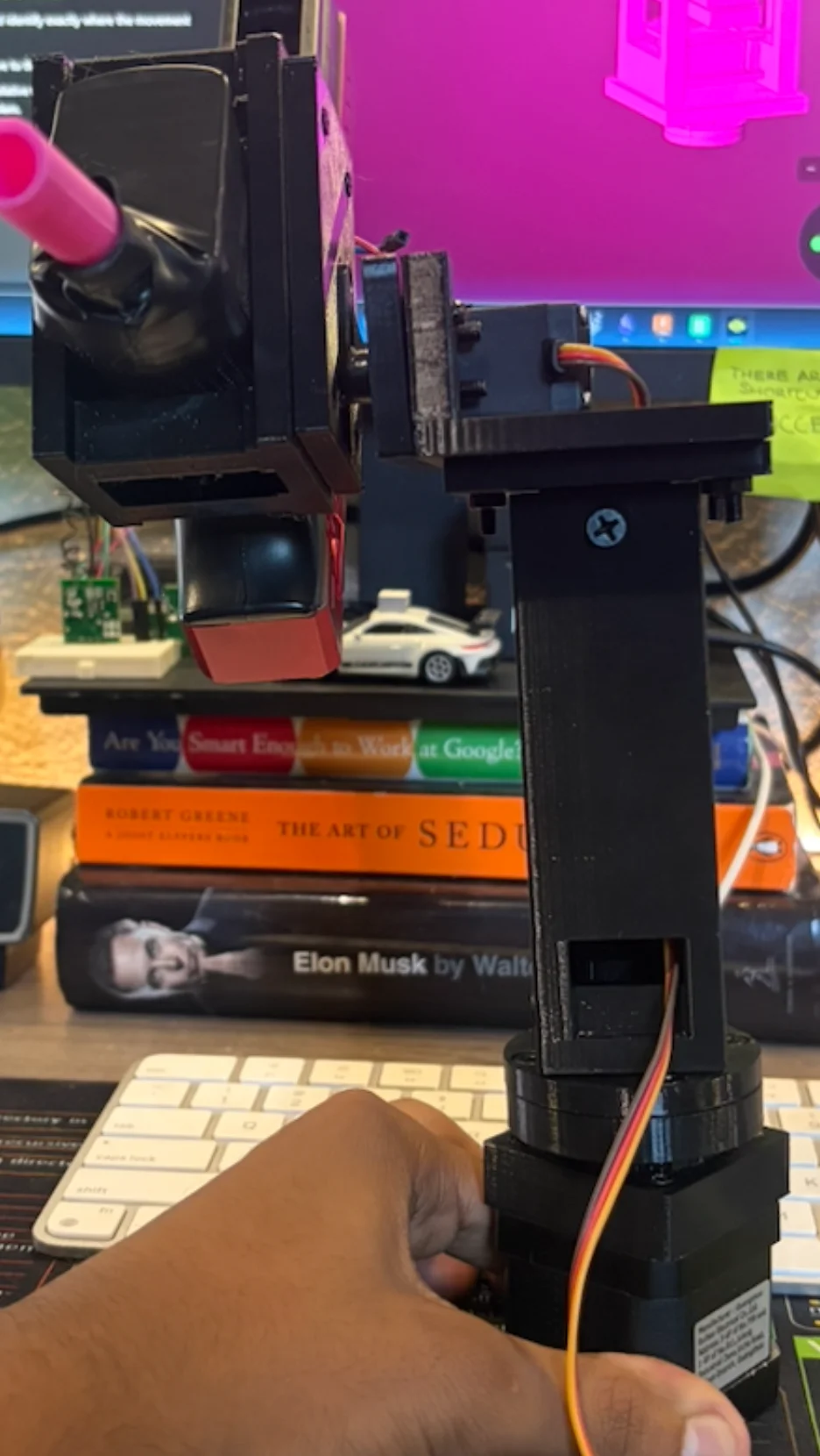 My hand steadies the NEMA 17 base while the early printed tower and mounted toy blaster lean to one side.